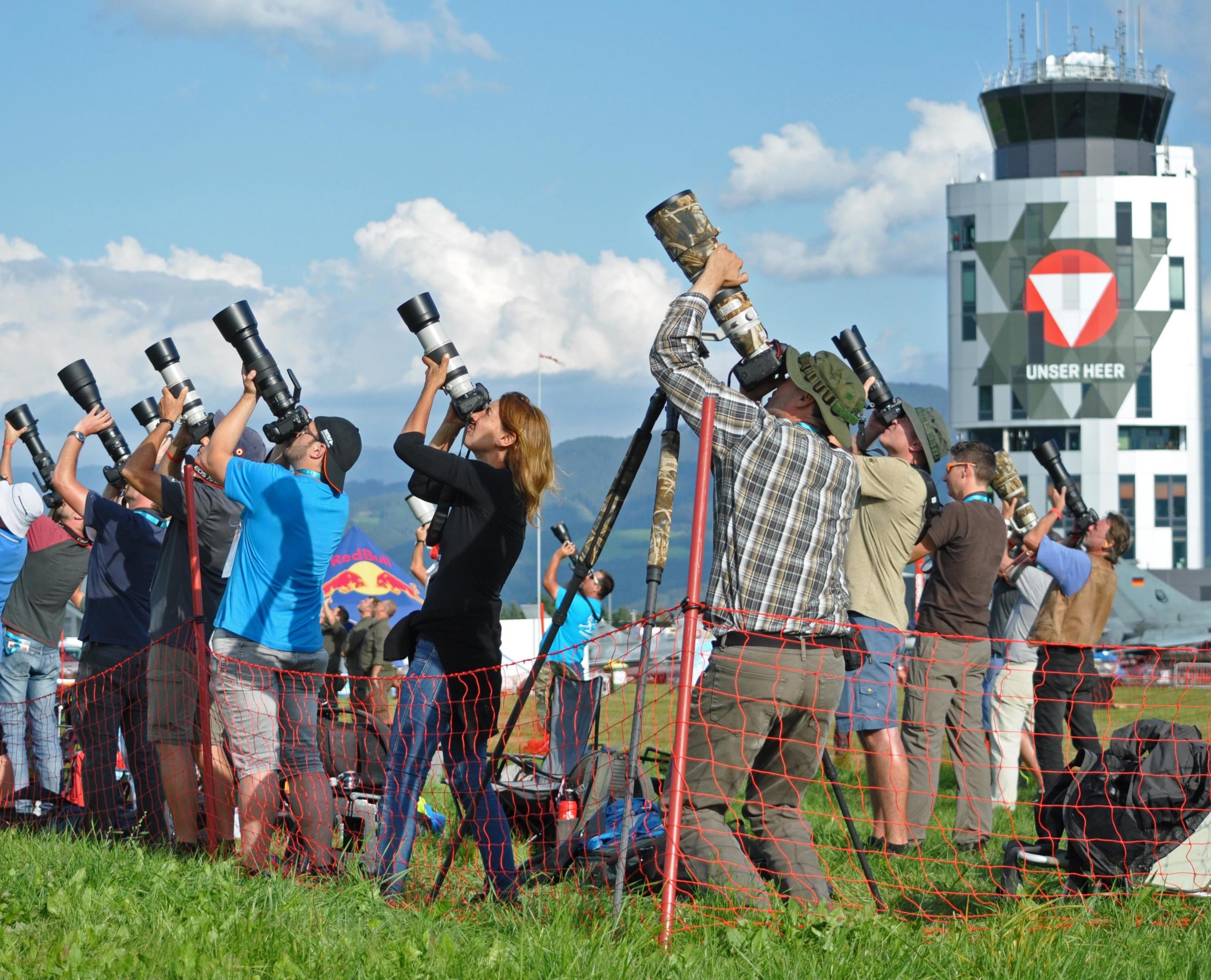 Eine Gruppe von Spottern mit grossen Kameraobjektiven in Richtung Himmel. A group of spotters with large camera lenses pointed towards the sky.