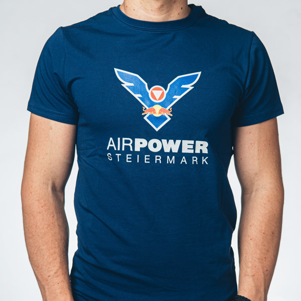 Person, die ein marineblaues „Airpower Steiermark“-T-Shirt mit einem stilisierten Vogellogo auf der Brust trägt.