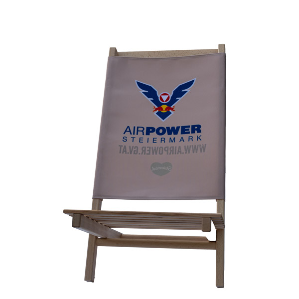 Ein beiger Klappstuhl mit „Airpower Steiermark“ und Adler-Logo-Aufdruck auf der Rückenlehne.