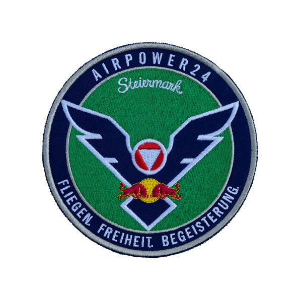 Kreisförmiges Logo mit Flügeln, Stieremblem und Text „AIRPOWER24“, „Steiermark“ und „FLIEGEN, FREIHEIT, BEGEISTERUNG“.